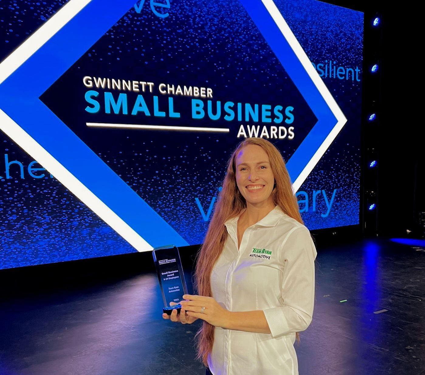 Woman holding an award at the Gwinnett Chamber Small Business Awards stage