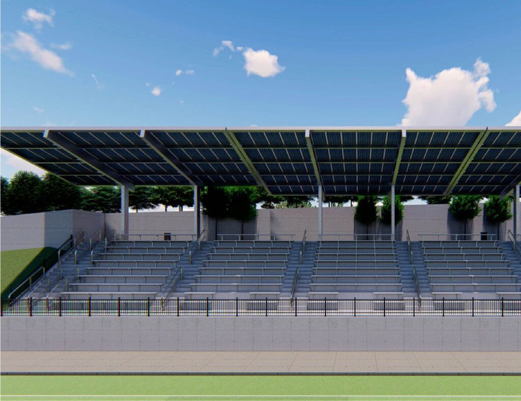 Empty stadium stands under a large solar-panel roof on a clear day