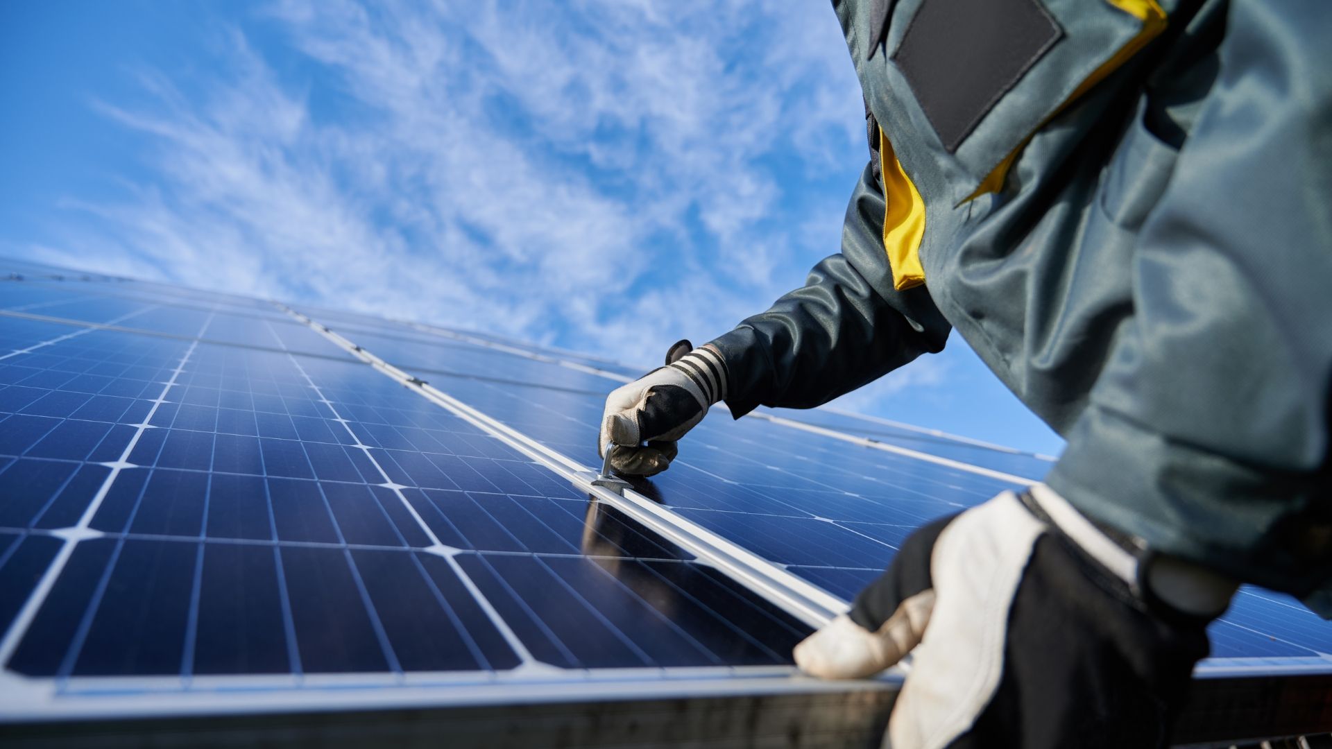 Worker cleaning solar panels under a blue sky