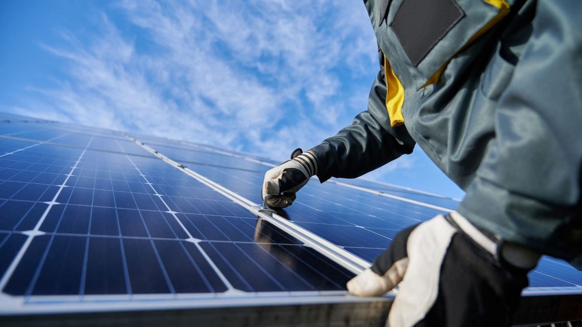 Worker cleaning solar panels under a blue sky