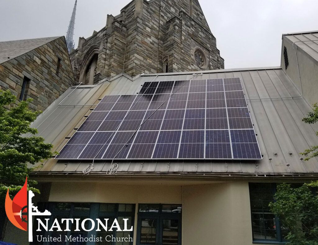 Solar panels on a sloped church roof beside stone architecture and a National Church sign.