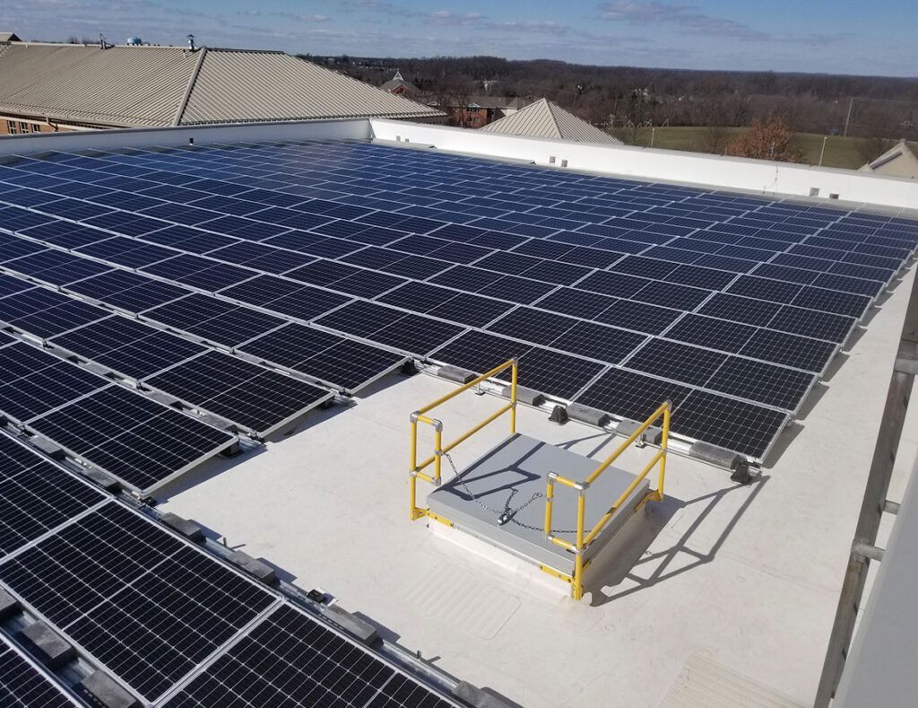 Rooftop solar panel array with a small yellow-railed maintenance platform in the center