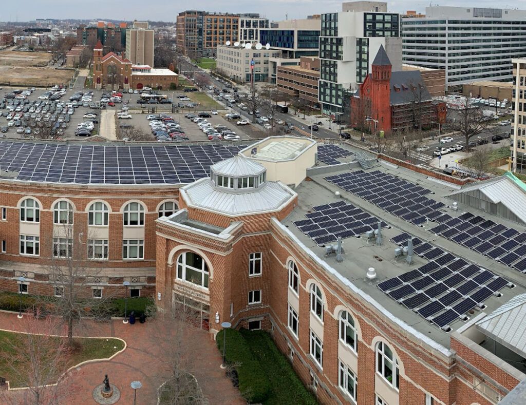 Aerial view of a brick building with solar panels on the roof in a city downtown.
