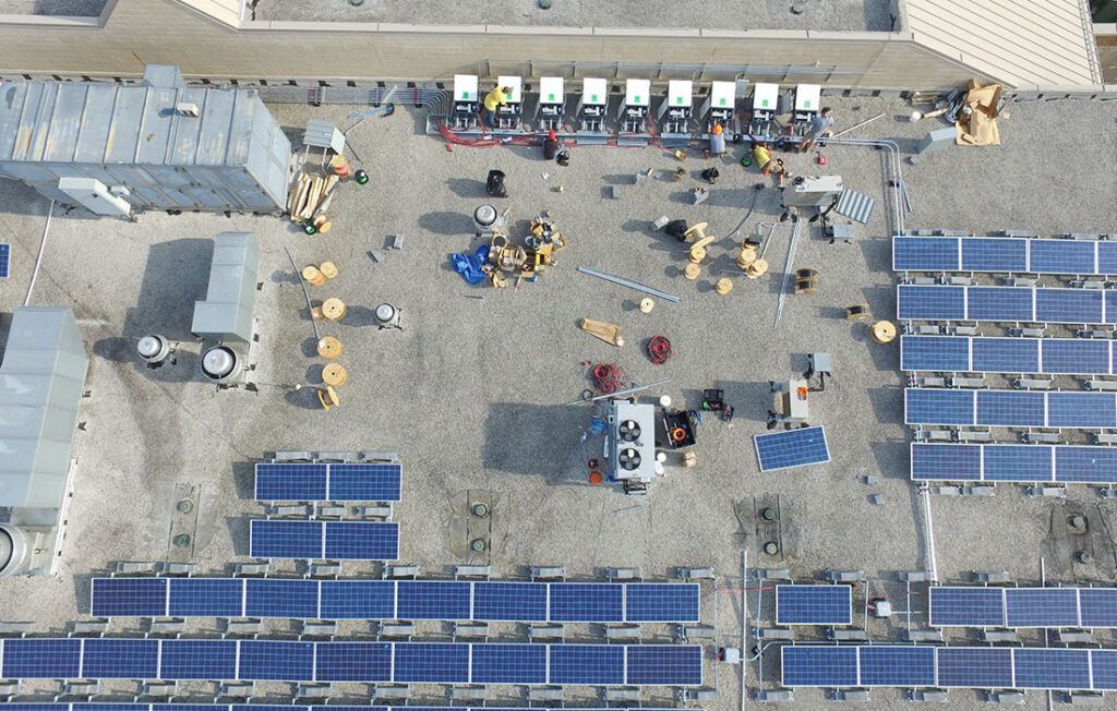 Aerial view of a rooftop solar installation with workers and equipment on the roof.