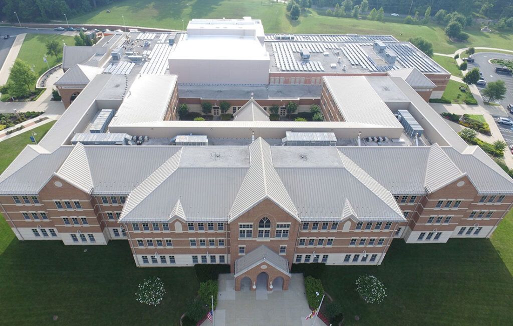 Aerial view of a large brick school building with a central entrance and surrounding green lawn.