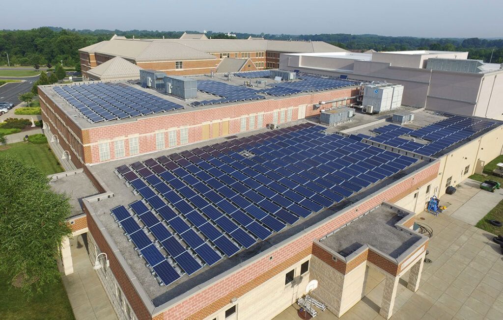 Aerial view of a building complex with large rooftop solar panels and surrounding industrial structures.