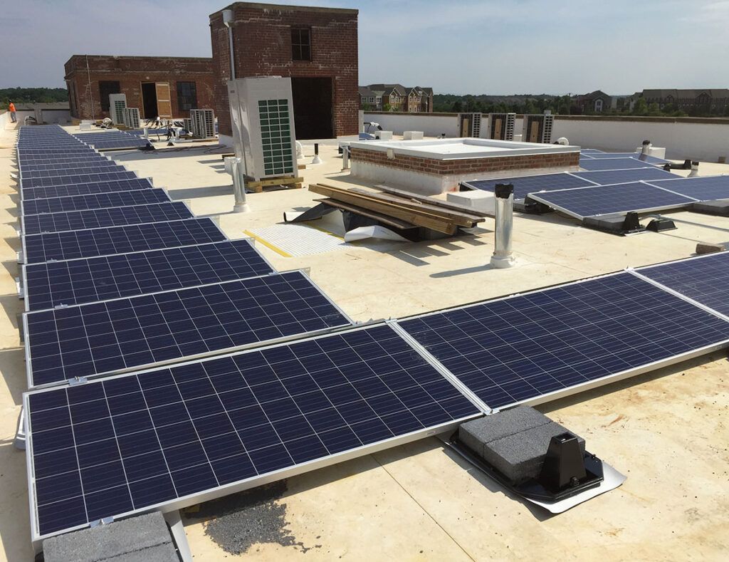Rooftop with rows of blue solar panels and white equipment under a clear sky