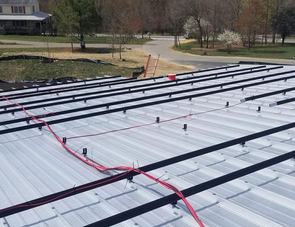 Solar panel array under construction beside a road, with red cables across the panels.