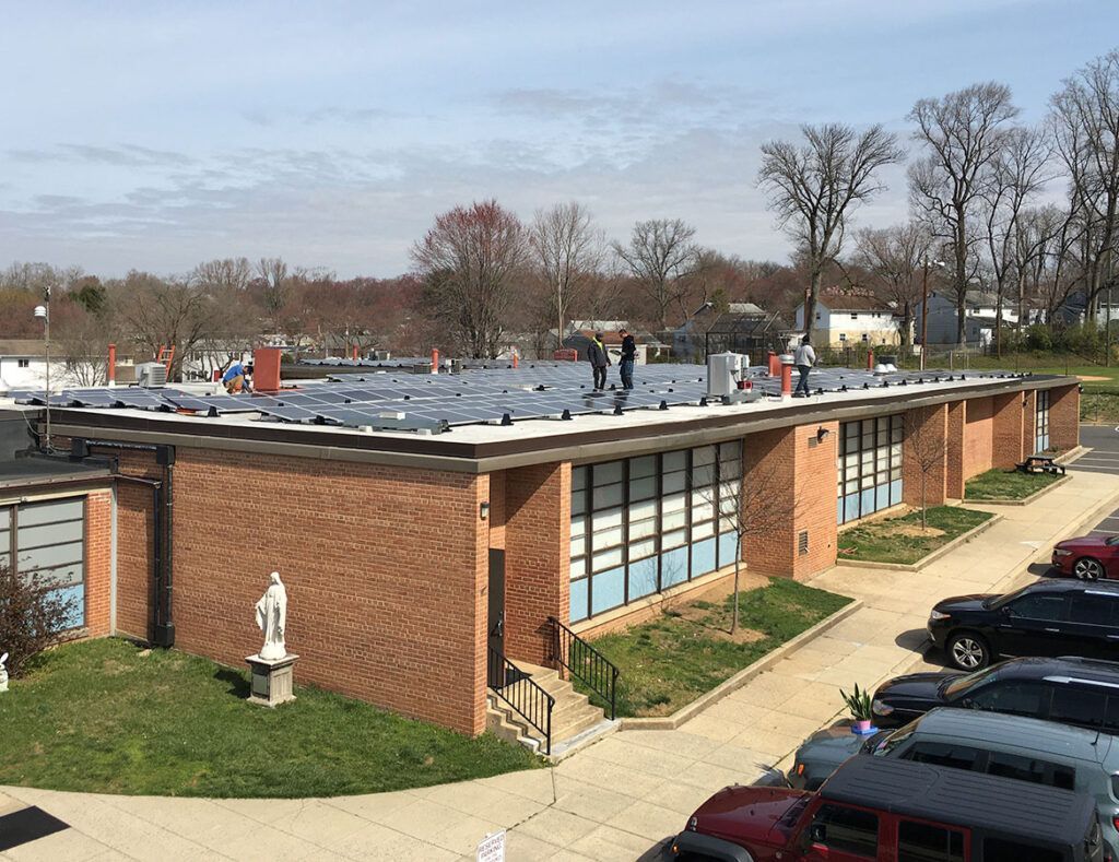 Low brick office building with a flat roof, parking lot, and trees in the background