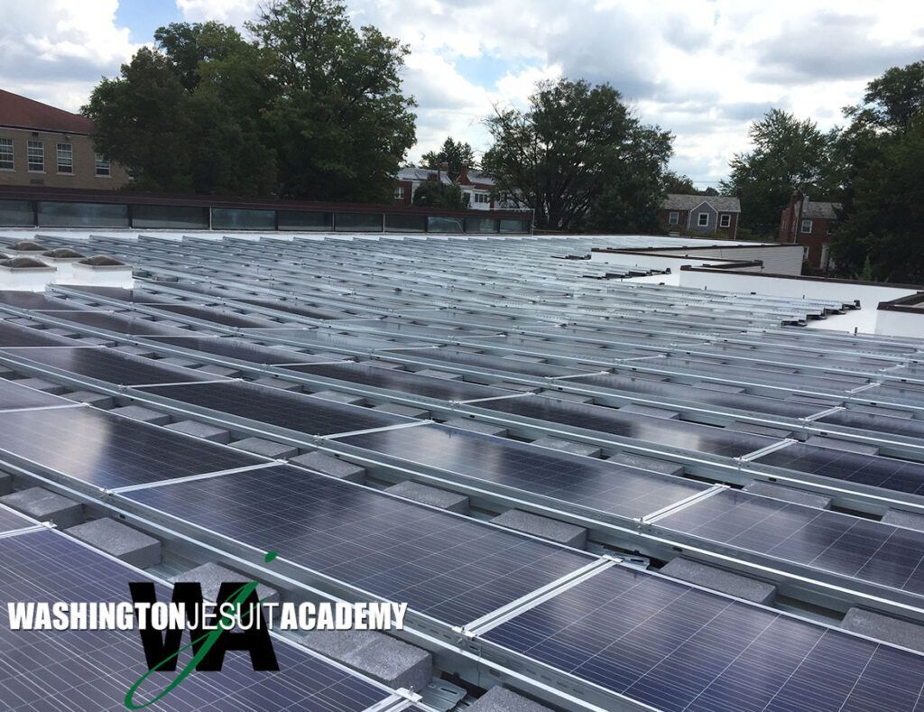 Solar panels covering a rooftop at Washington Jesuit Academy under a partly cloudy sky