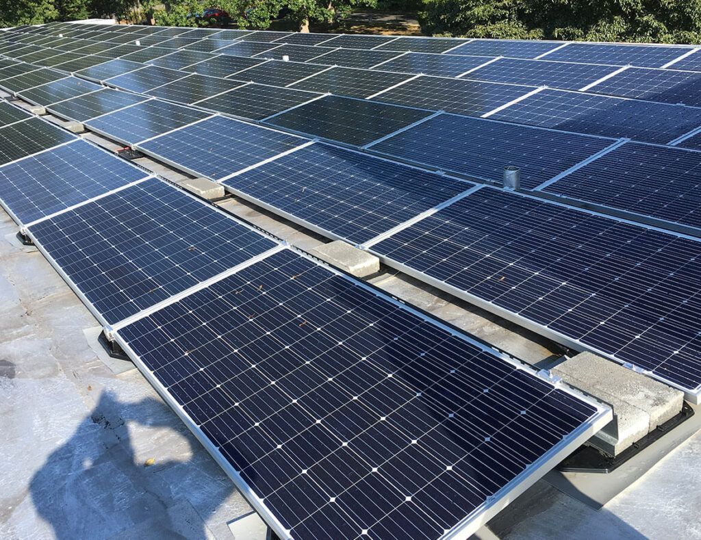 Rows of blue solar panels in a large outdoor solar farm under bright sunlight