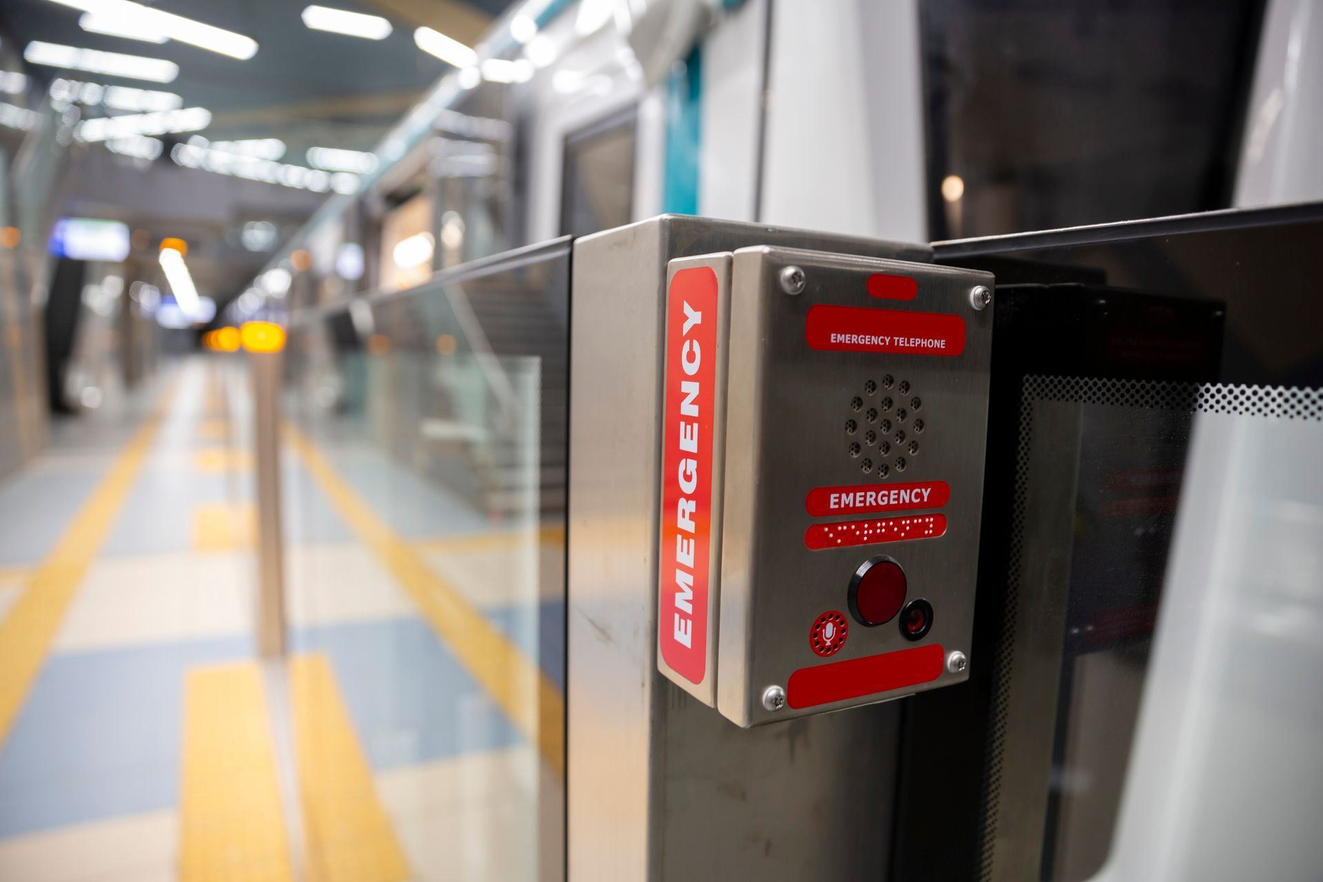 Emergency call button on a train platform. Red box with button and speaker next to glass door. Emergency call button on a train platform. Red box with button and speaker next to glass door.