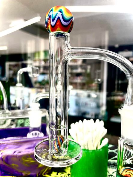 A close up of a glass pipe with a rainbow ball on top of it.