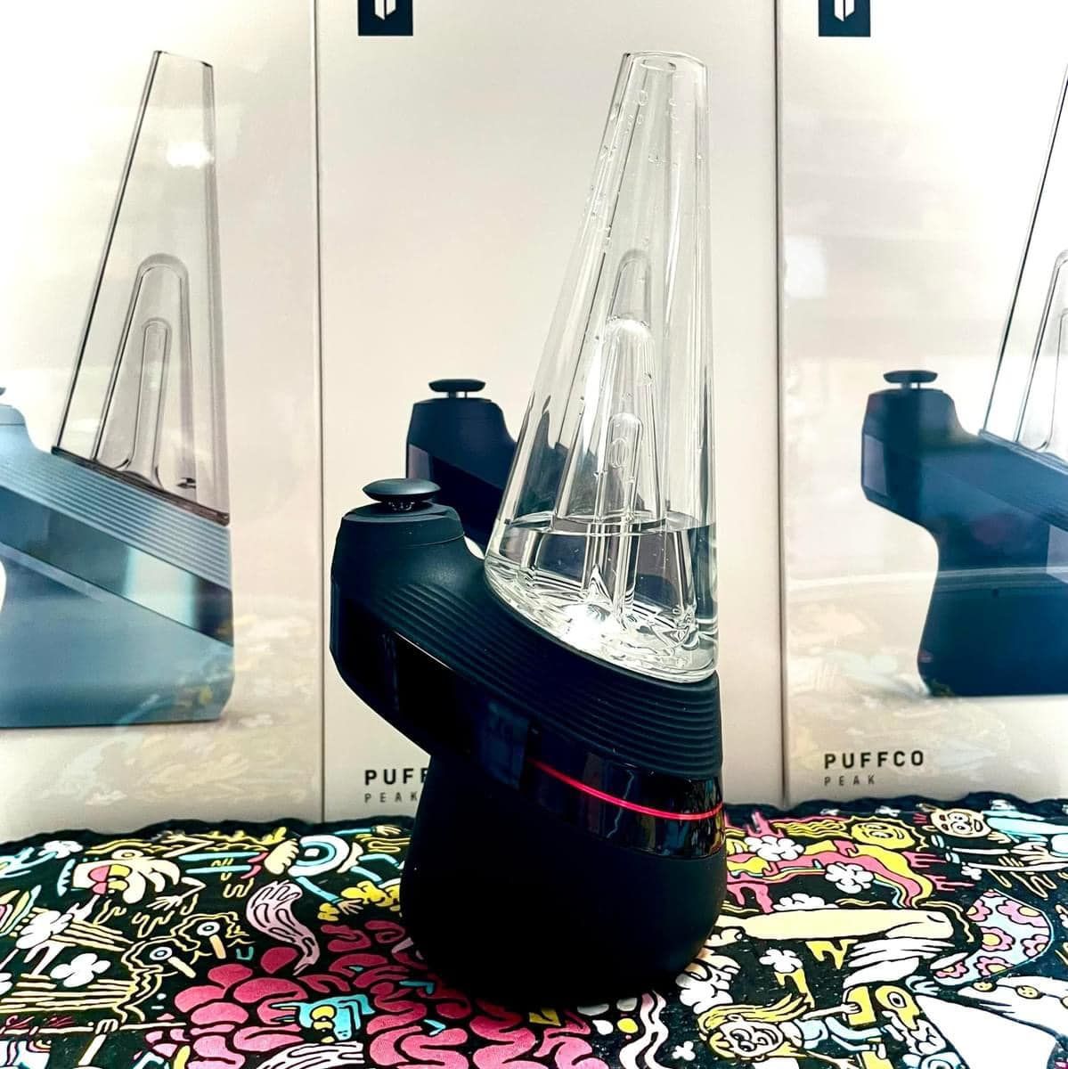 A puffco device is sitting on a table next to boxes.
