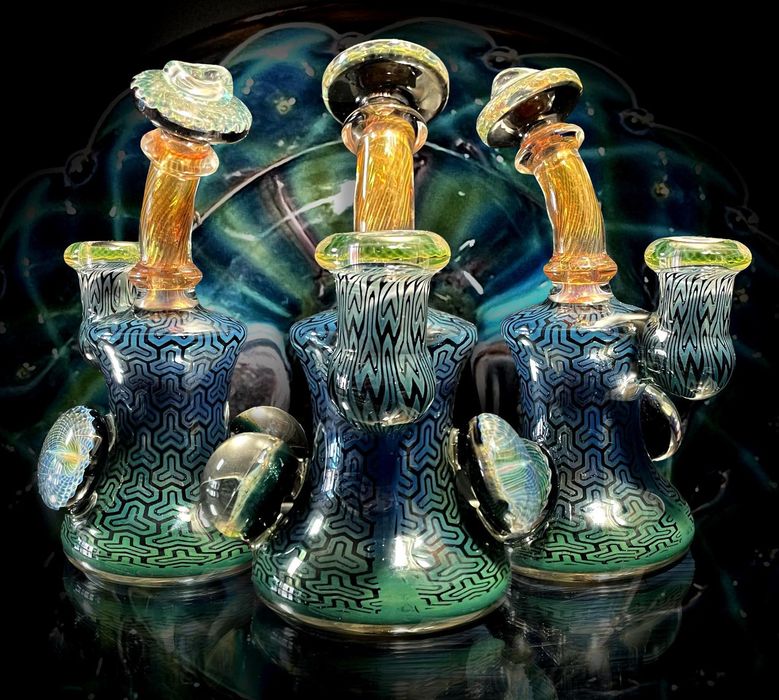 Three glass bongs are sitting on top of each other on a table.