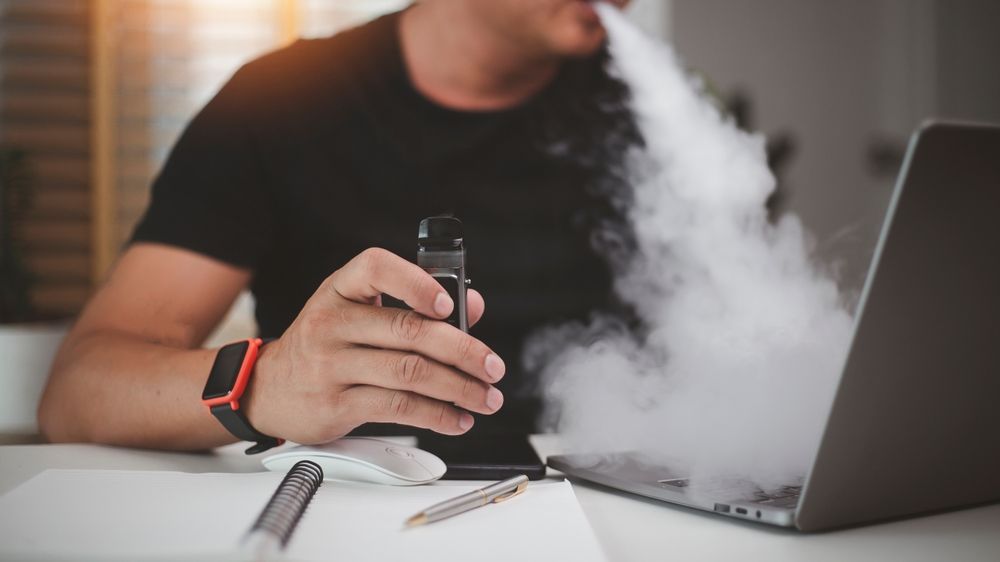 a man blowing smoke into his computer 