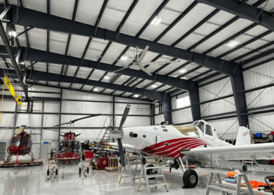 A red and white plane is parked inside of a hangar.