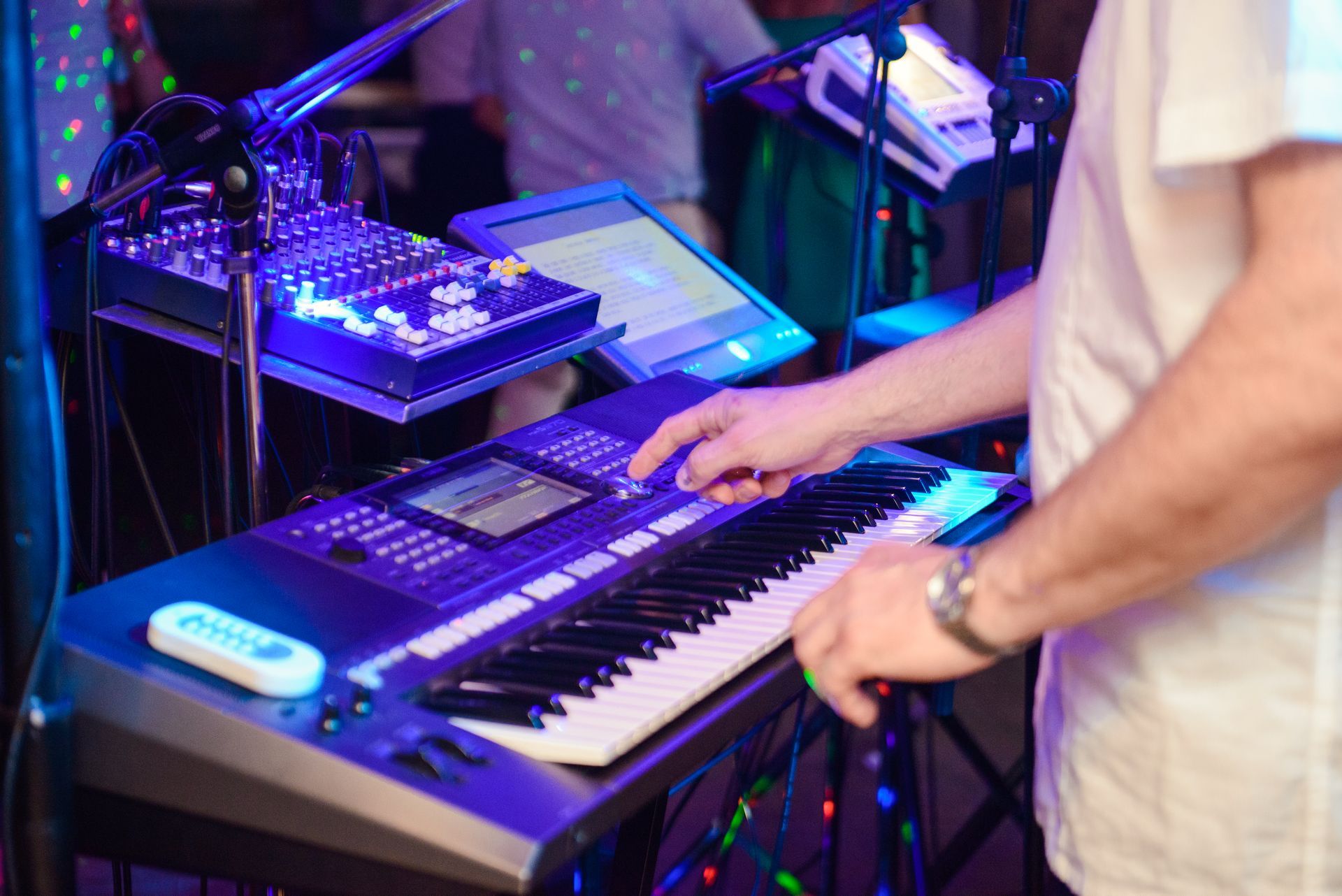 Person playing a keyboard on stage under blue and purple lights