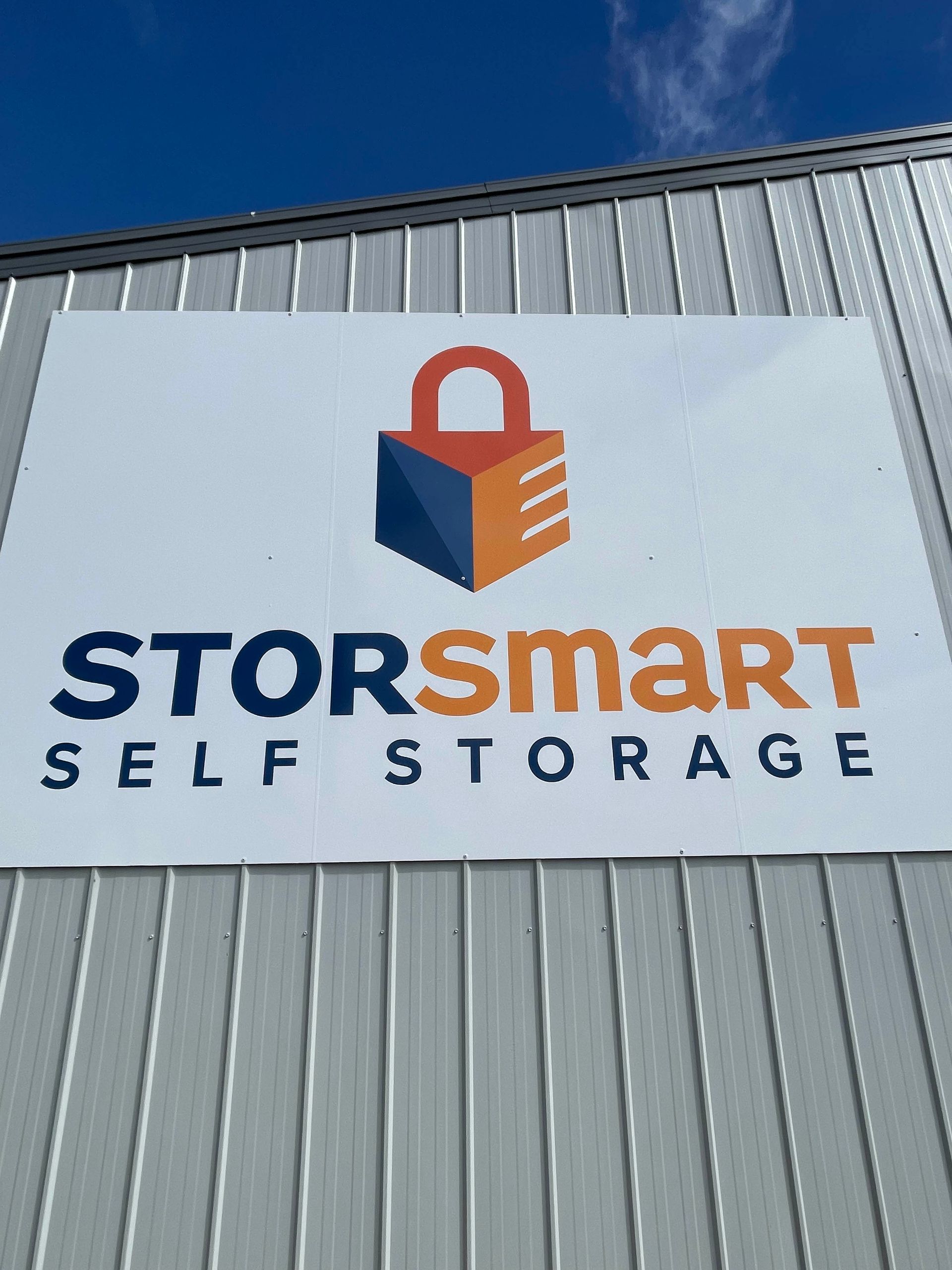 StorSmart Self Storage sign on a gray building under a blue sky