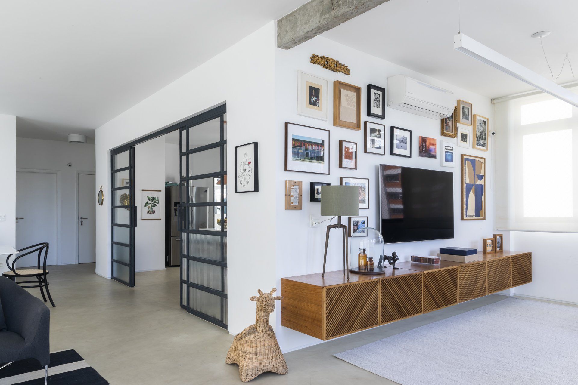 Uma sala de estar com porta de vidro deslizante e uma TV de tela plana na parede.