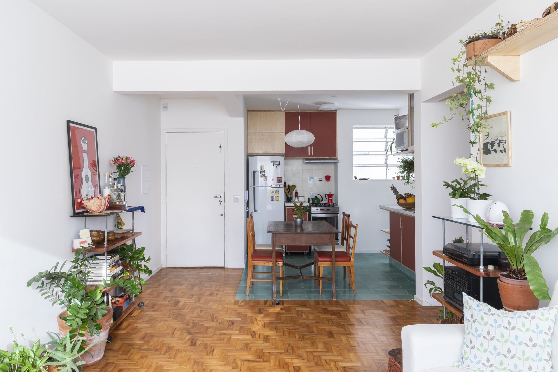 Uma sala de estar com mesa e cadeiras e uma cozinha ao fundo.