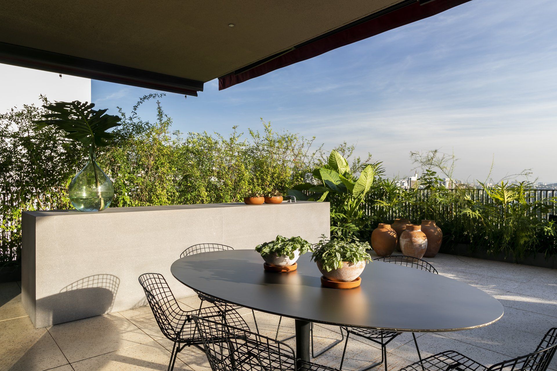 Um pátio com mesa e cadeiras e vasos de plantas.