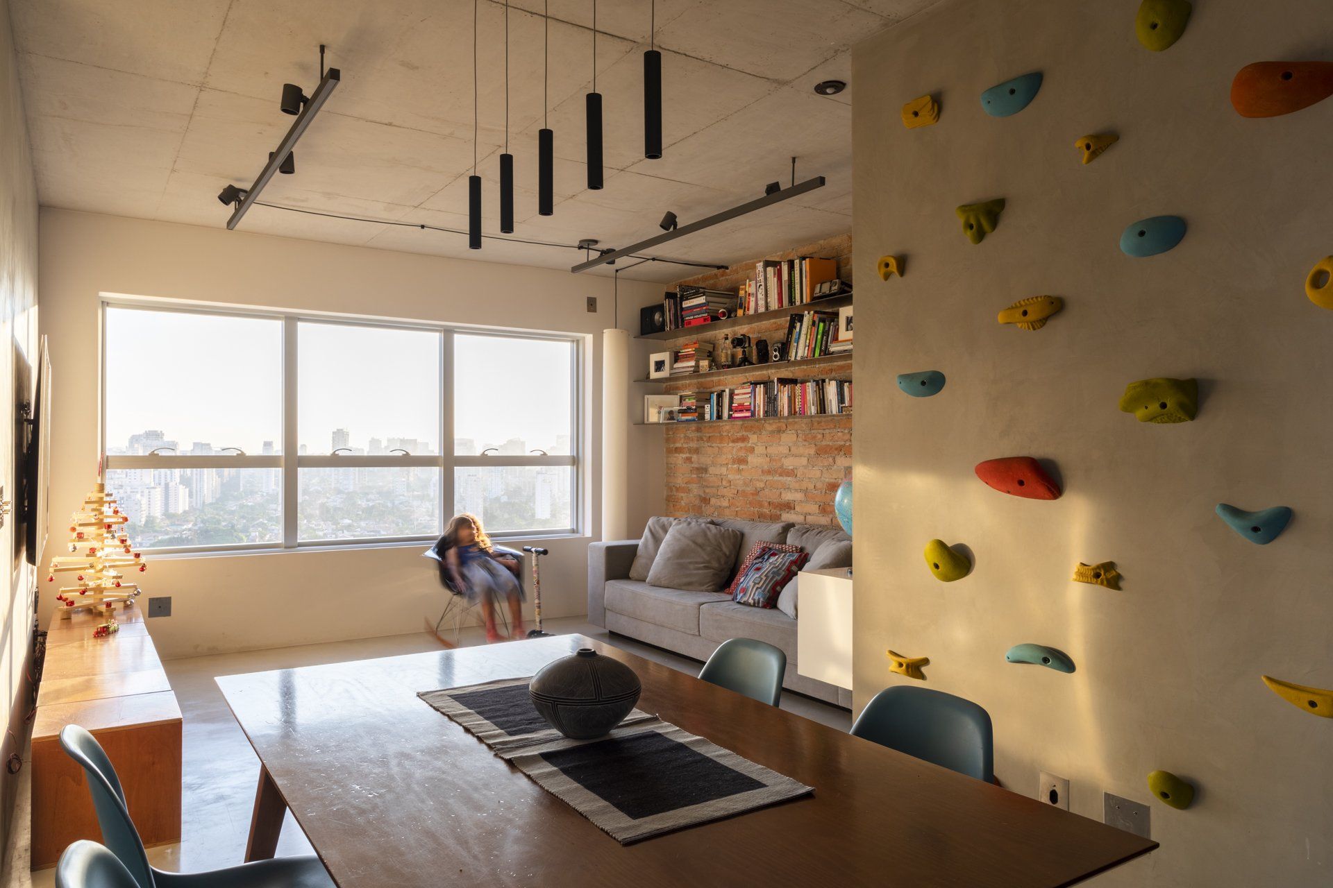 Uma sala de estar com parede de escalada e mesa de jantar.