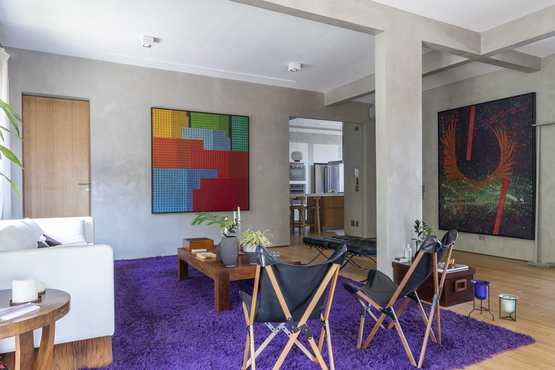 Uma sala com tapete roxo, cadeiras, sofá e mesa de centro.