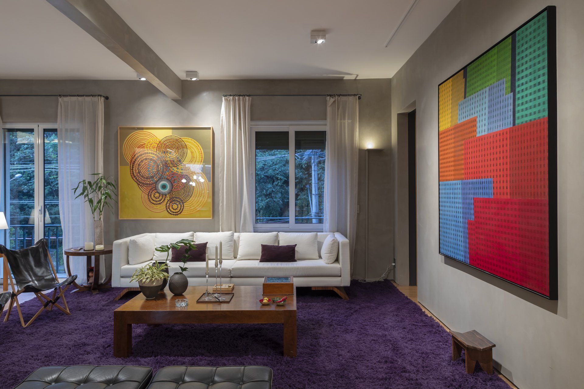 Uma sala com sofá branco e tapete roxo