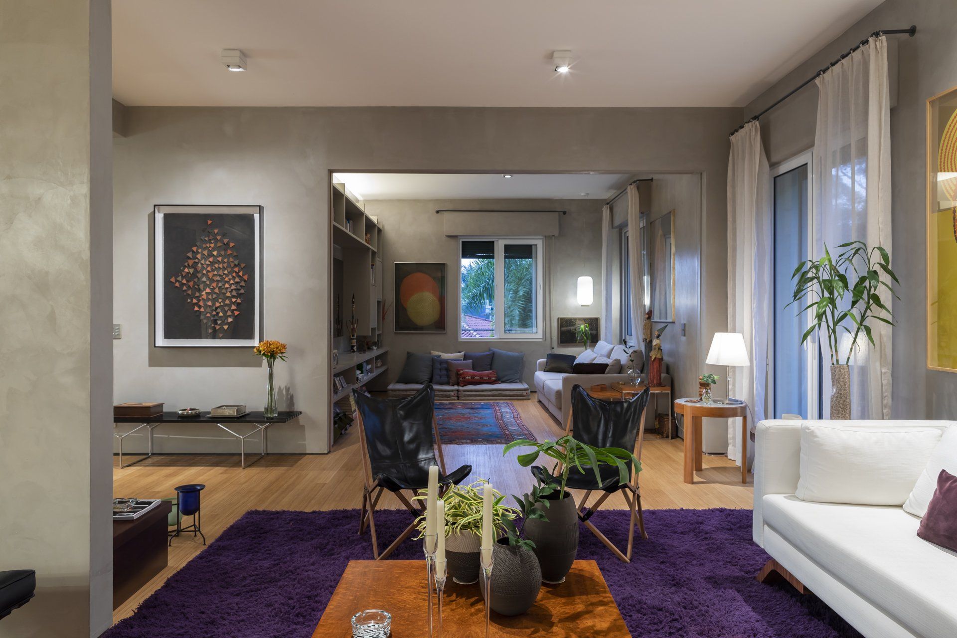 Uma sala de estar com tapete roxo e sofá branco