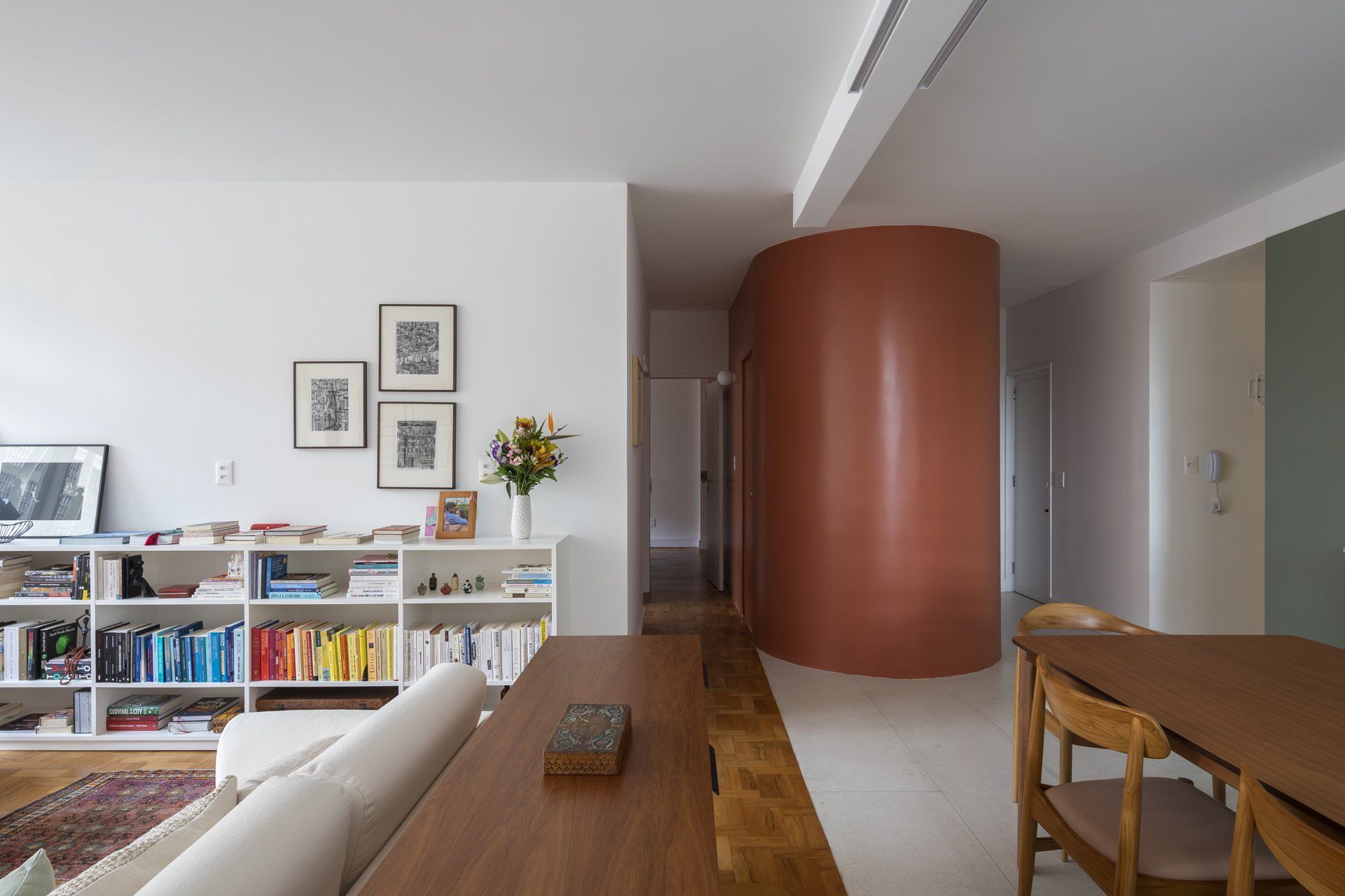 Uma sala com sofá, mesa e cadeiras e uma parede curva.
