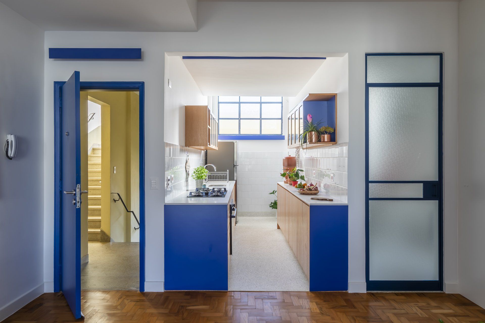 Uma cozinha com armários azuis e uma porta azul que dá para um banheiro.