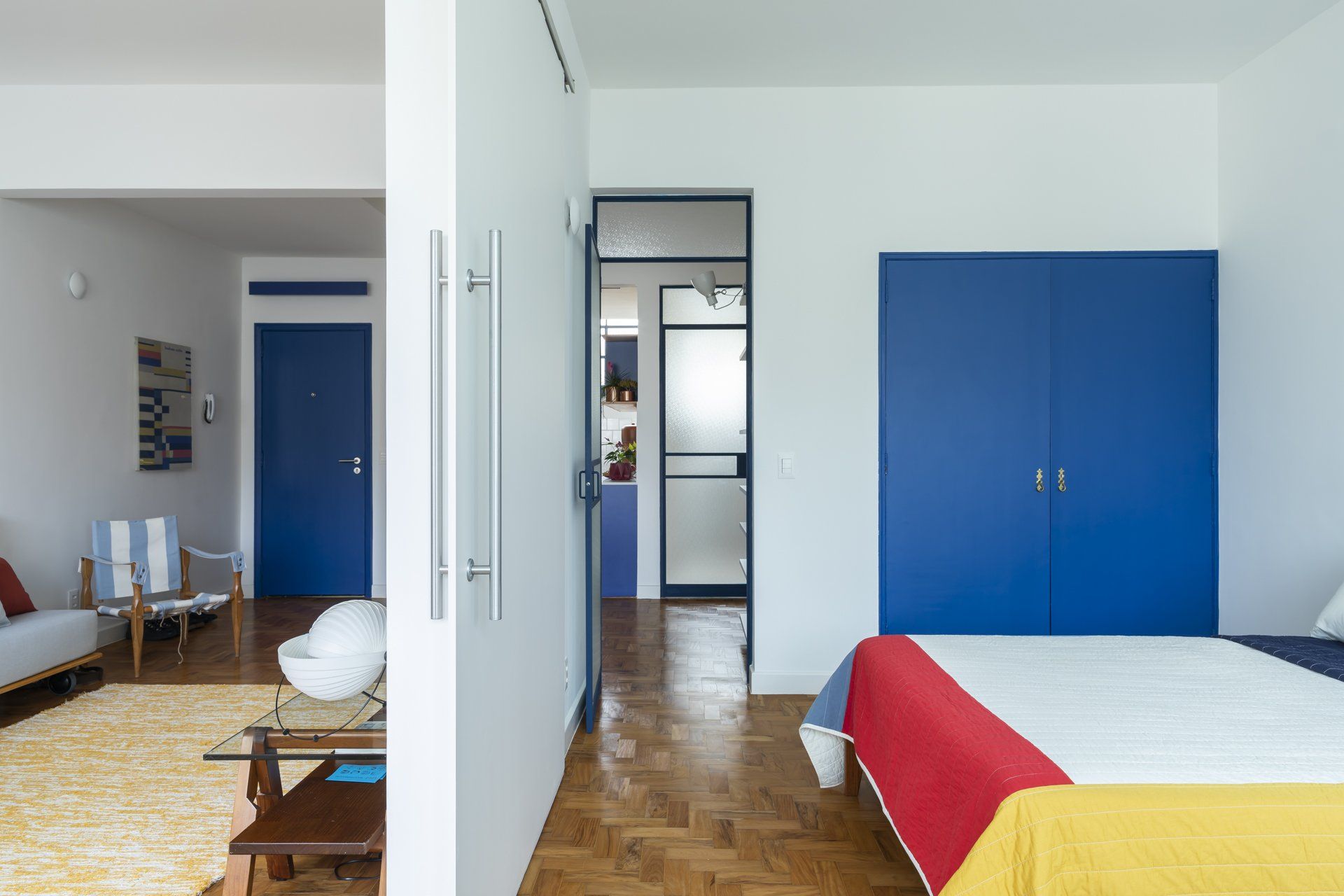 Um quarto com cama, cadeiras e porta azul.
