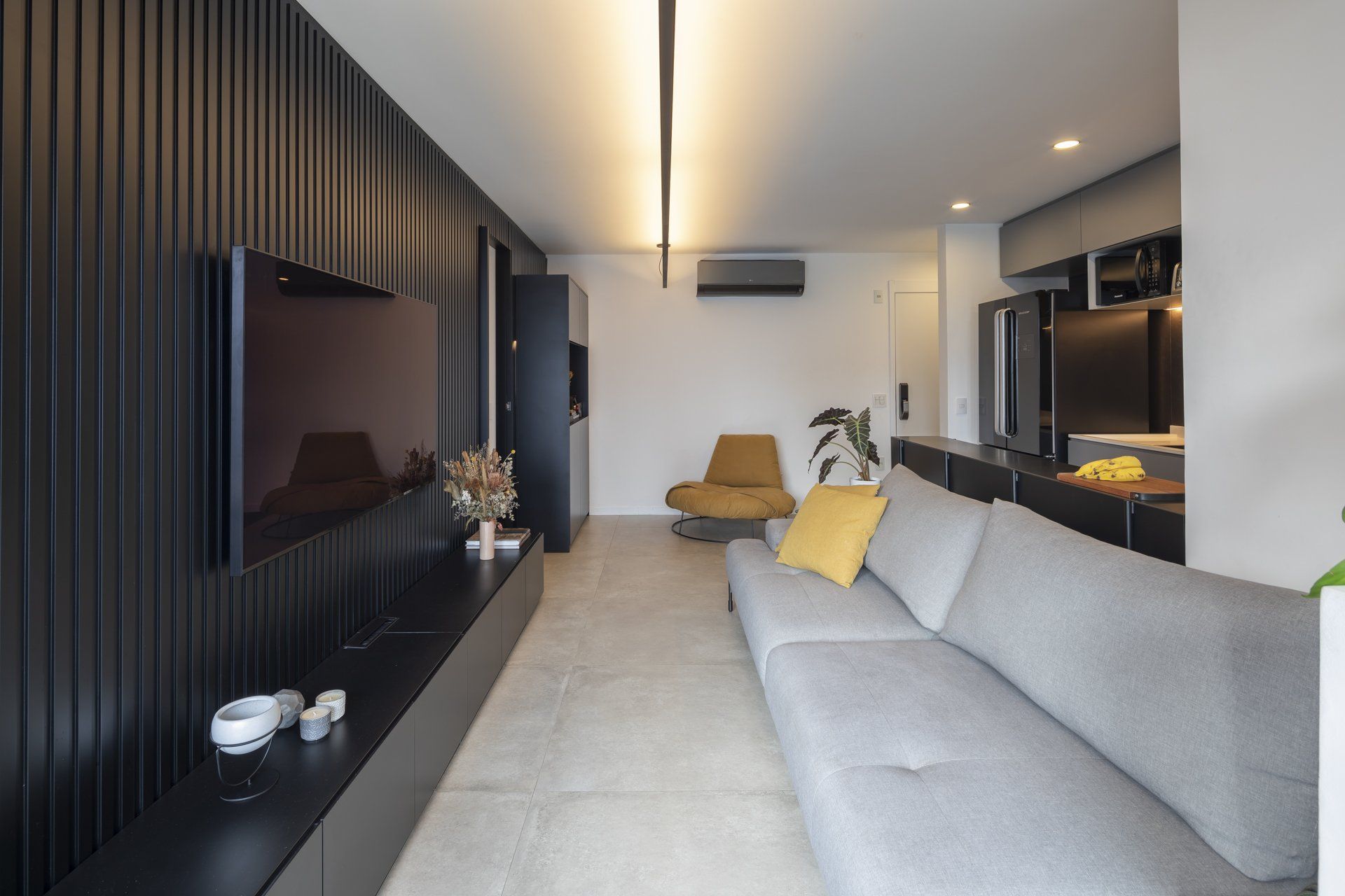Uma sala de estar com sofá, cadeira e televisão.