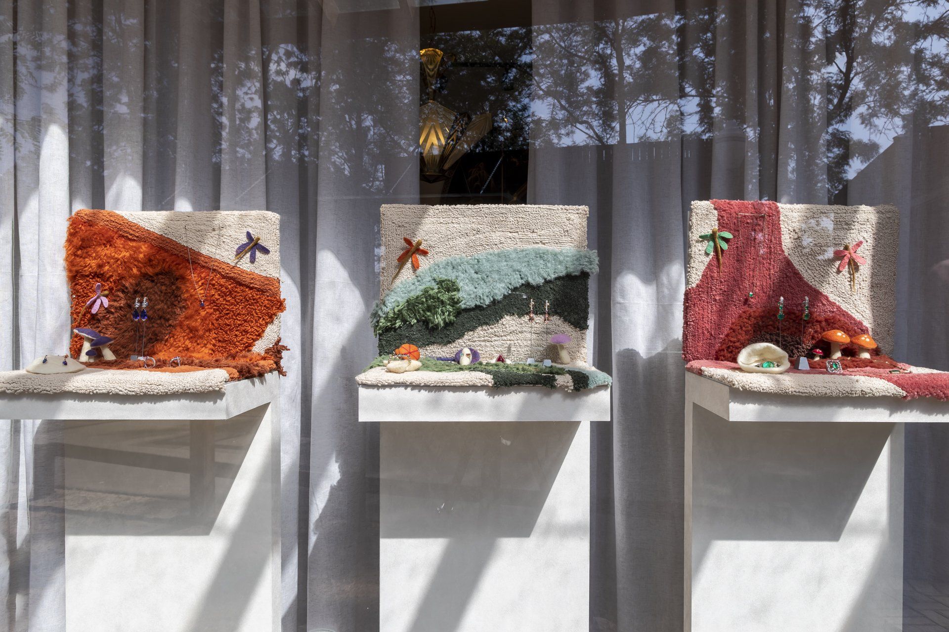 Três pinturas estão expostas em uma vitrine.