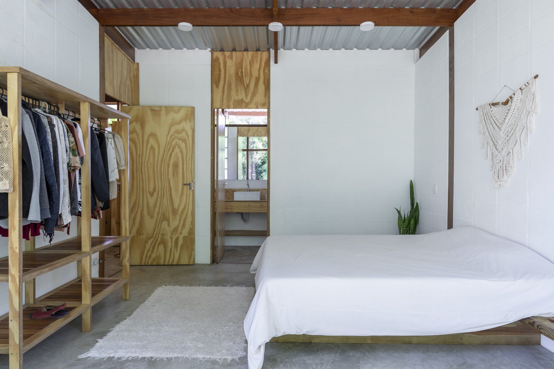 Um quarto com cama, armário e cabideiros.