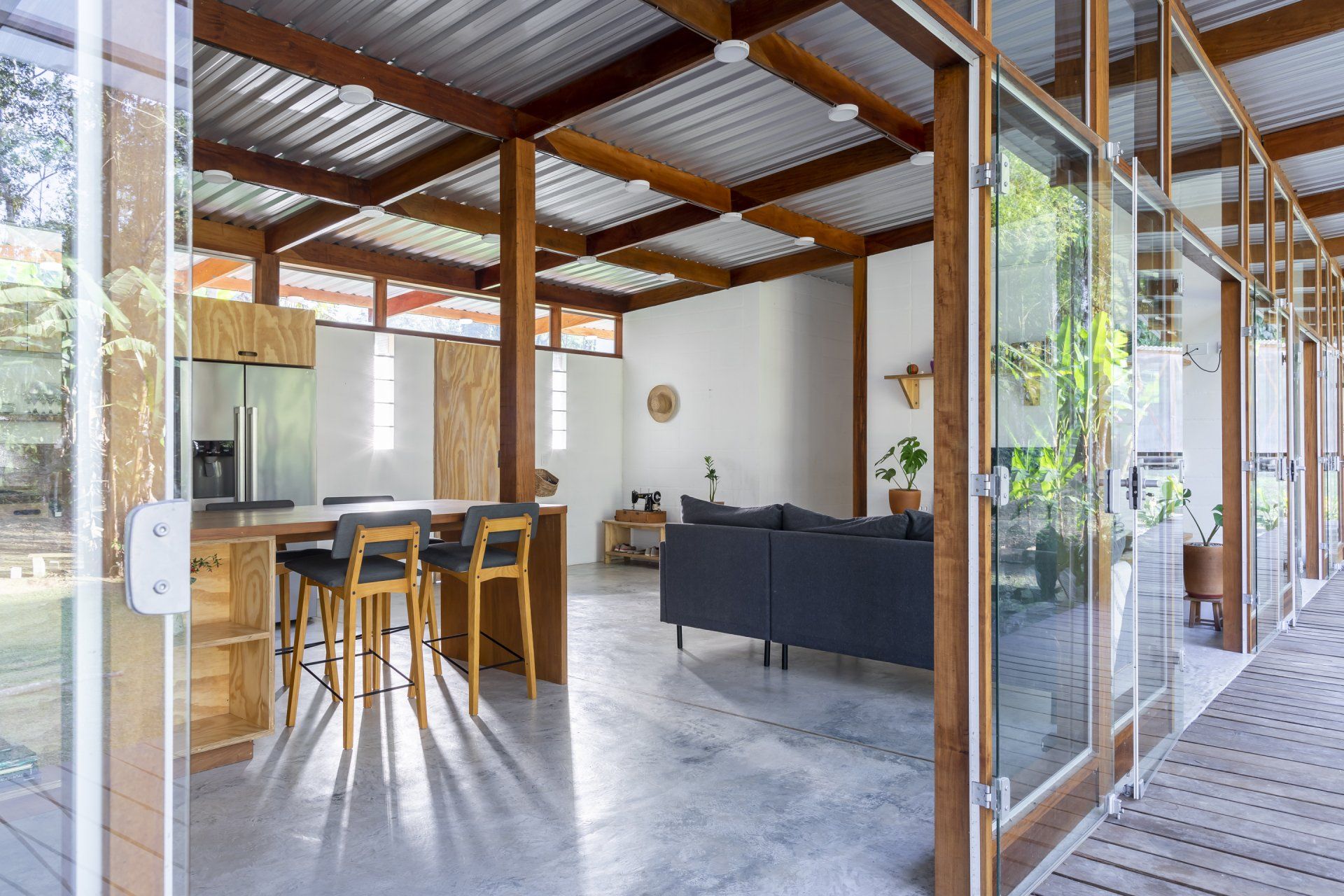Uma sala com sofá, mesa, cadeiras e geladeira.