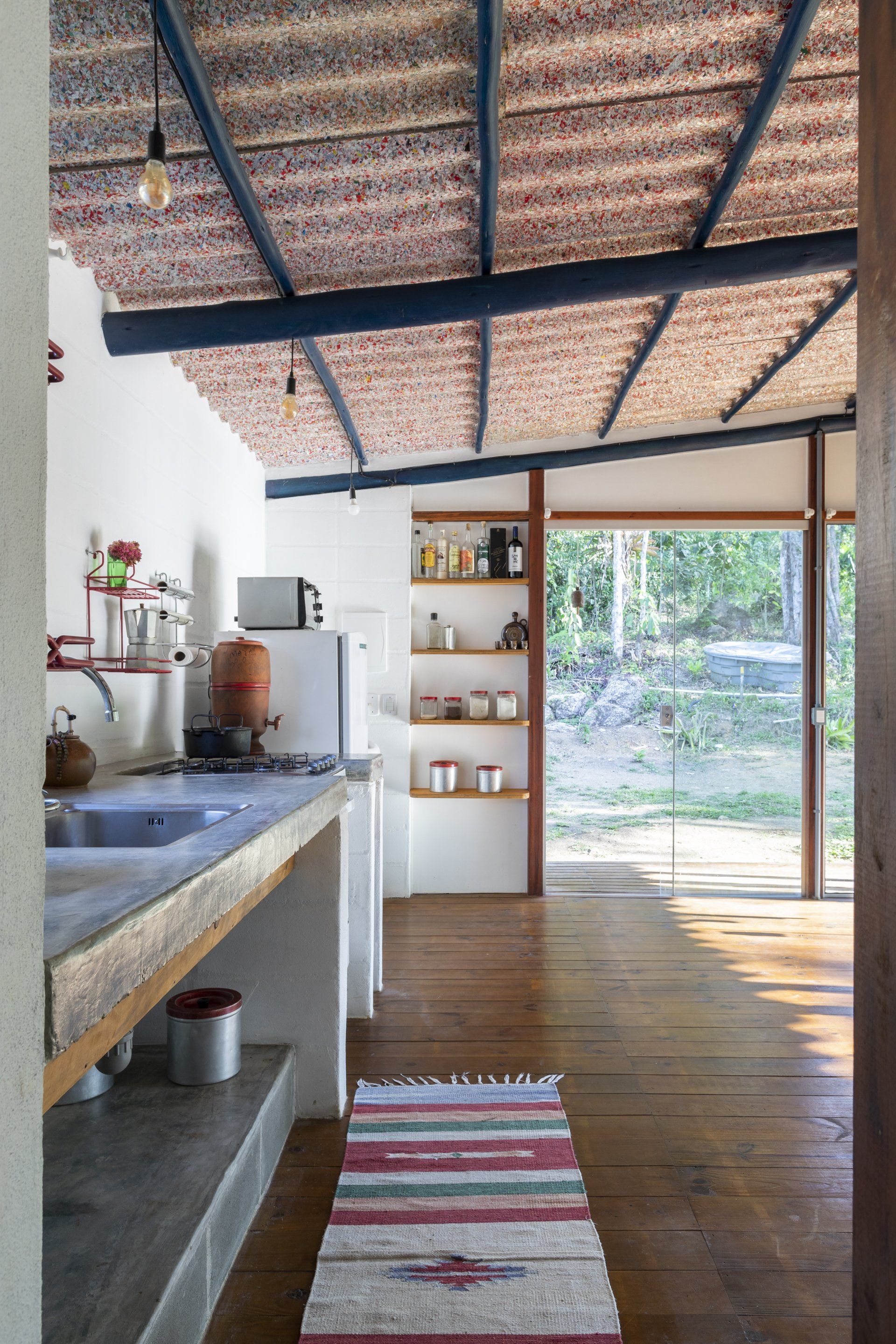 Uma cozinha com tapete no chão e uma grande janela.
