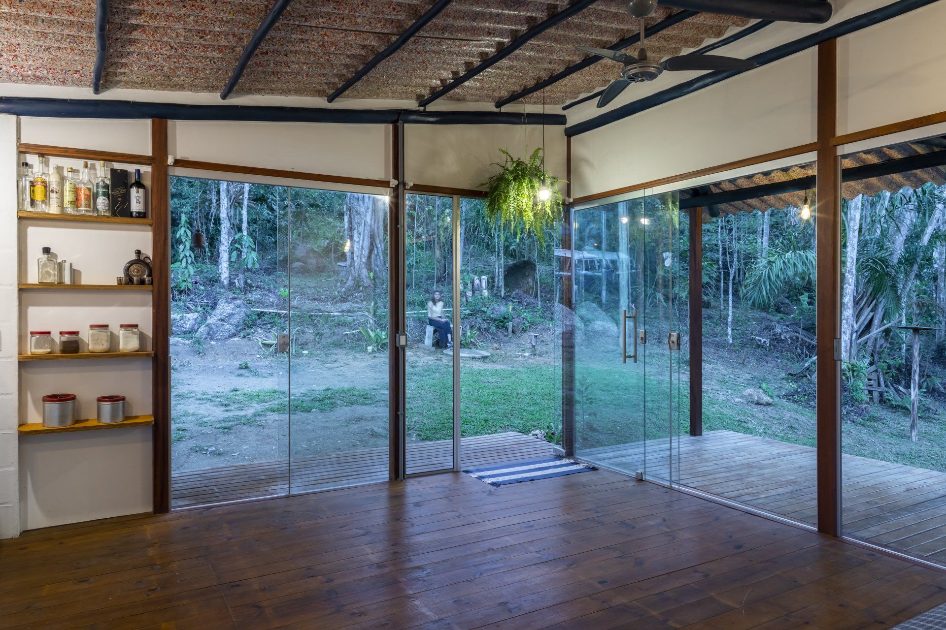 Uma sala com muitas janelas e piso de madeira.