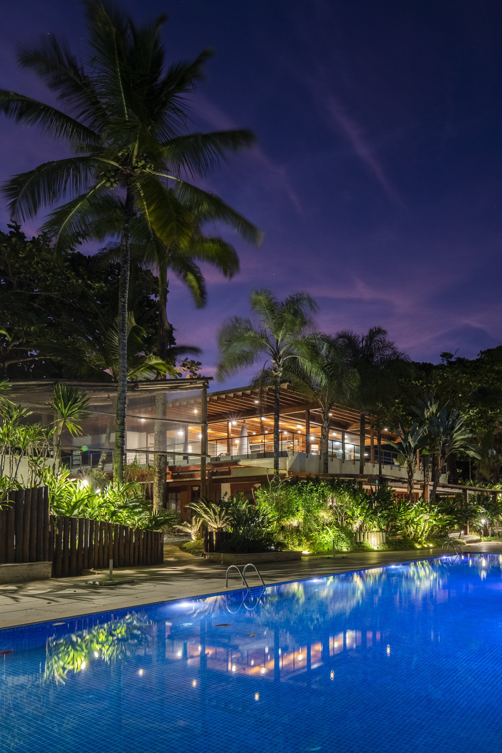 Uma grande piscina com uma casa ao fundo à noite