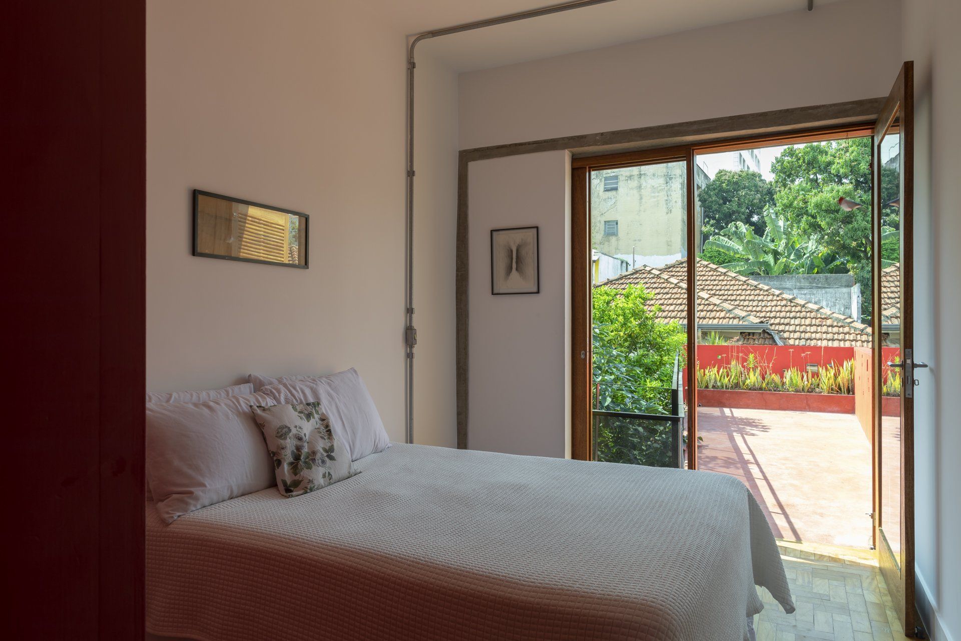 Um quarto com uma cama e uma porta de vidro deslizante que dá acesso a uma varanda.
