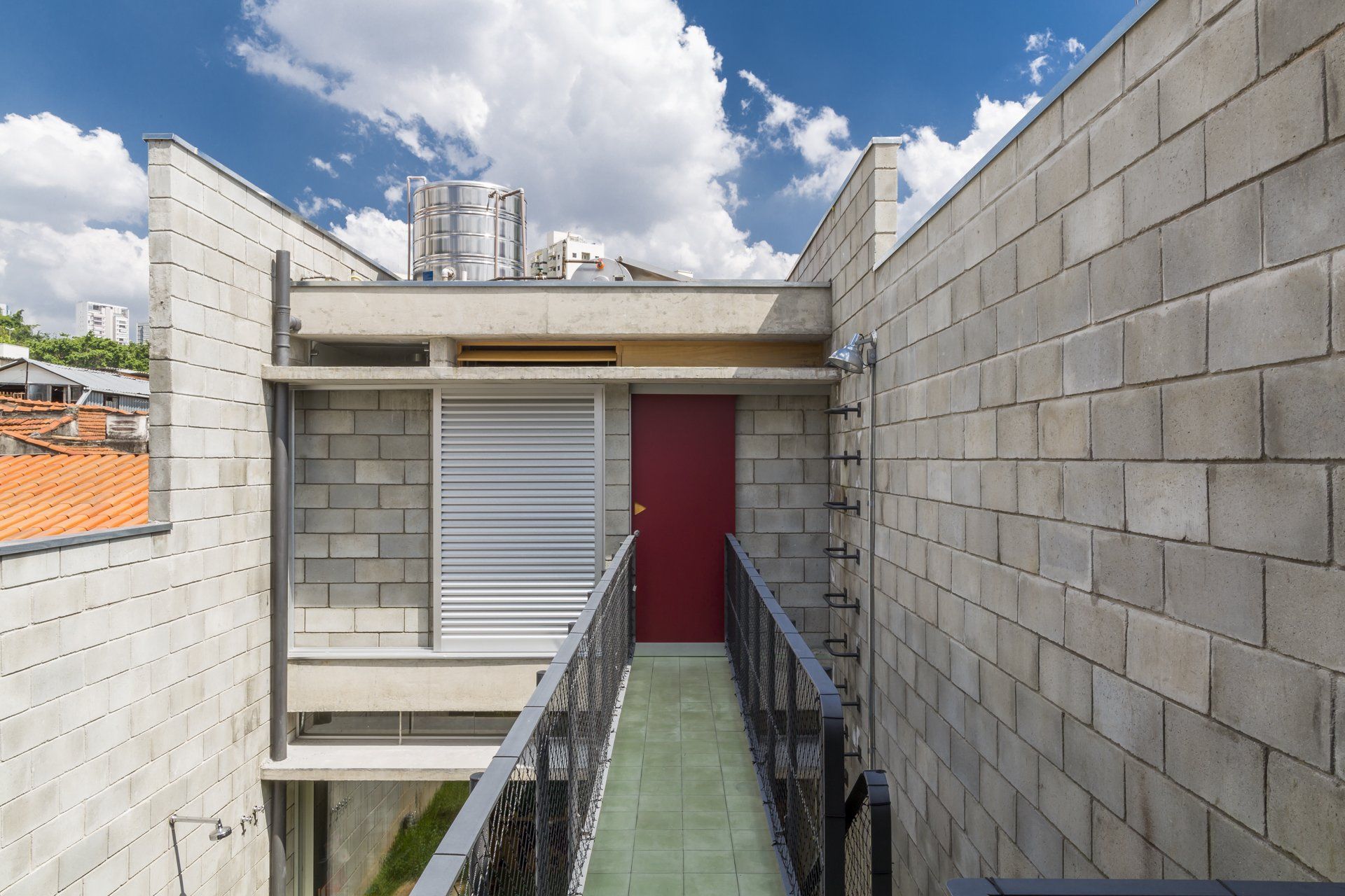 Um prédio de tijolos com uma porta vermelha e uma passarela que leva até ela.