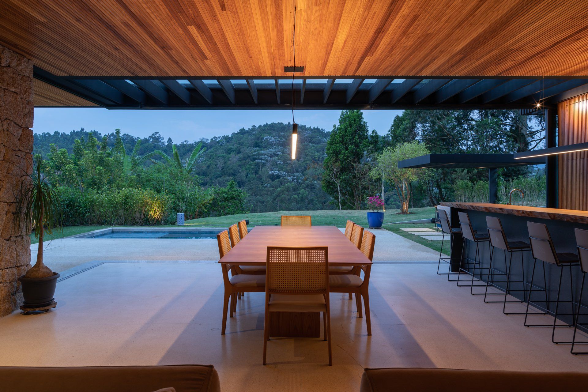 Uma sala de jantar com mesa e cadeiras e uma piscina ao fundo.