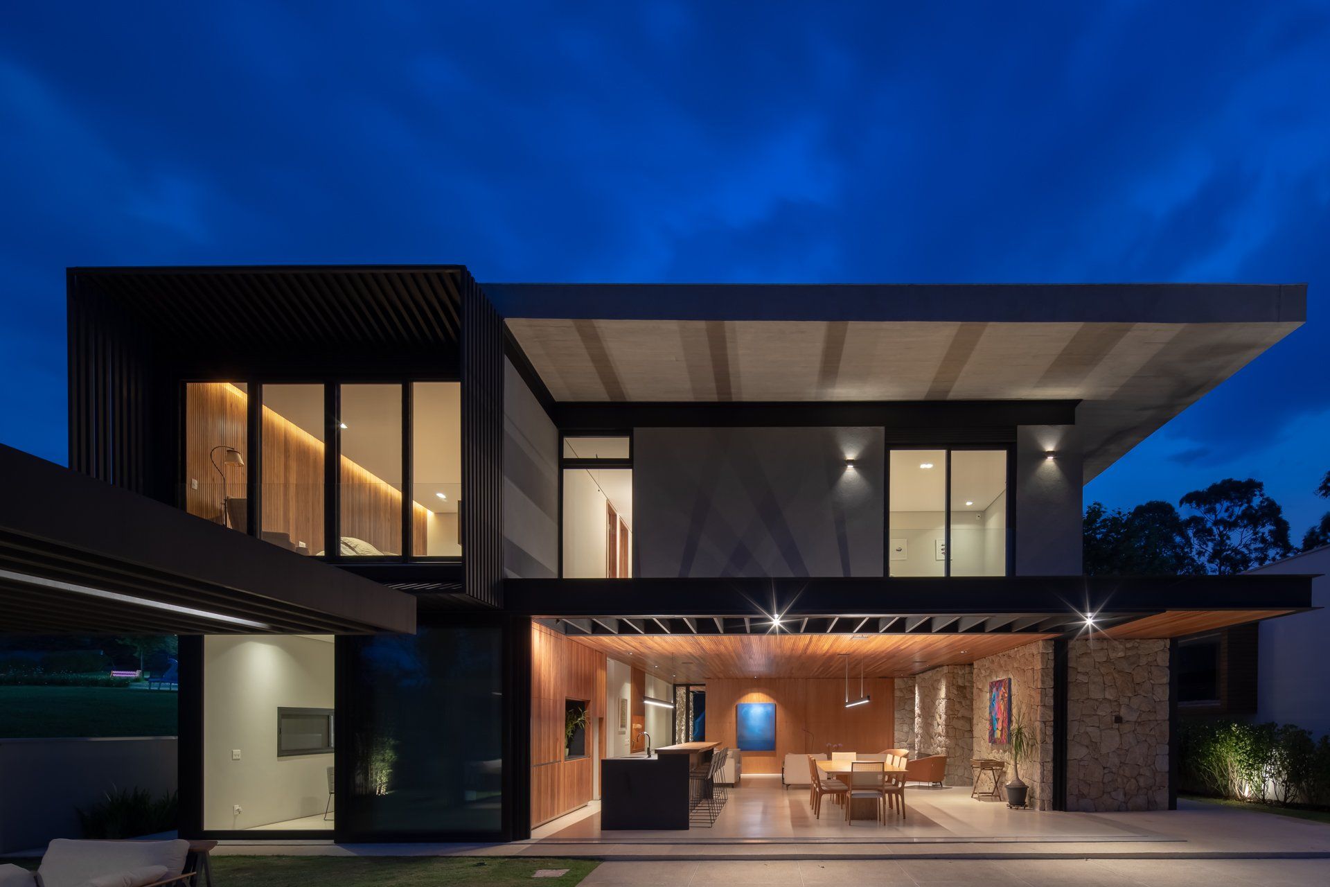 Uma casa moderna com muitas janelas fica iluminada à noite.