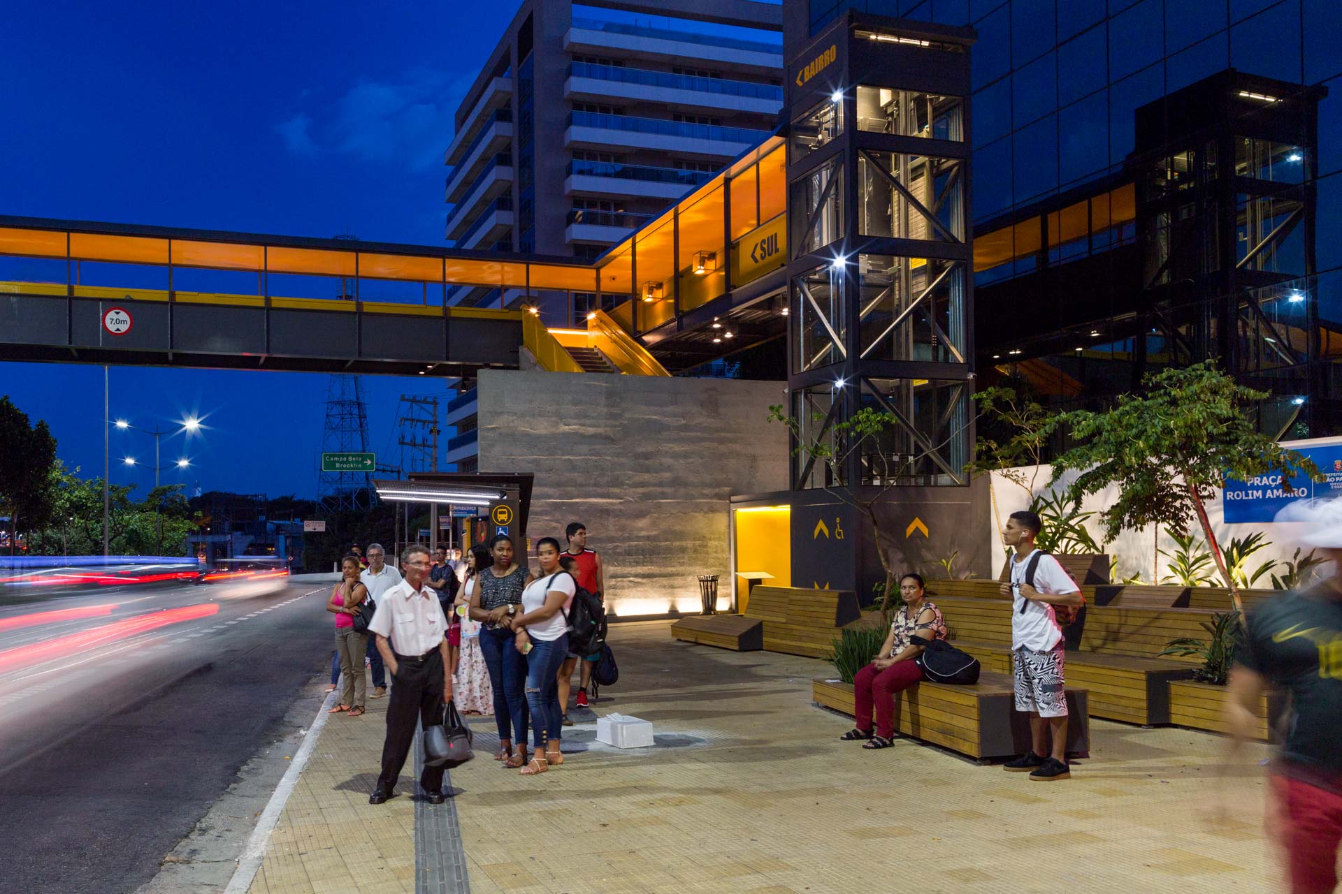 Um grupo de pessoas está parado na beira da estrada à noite.