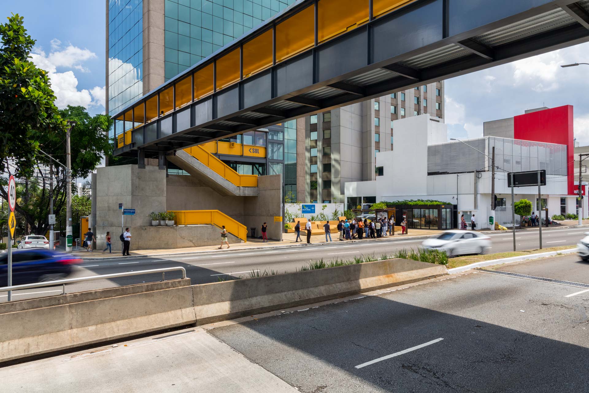 Uma ponte sobre uma rua de uma cidade com um prédio ao fundo.