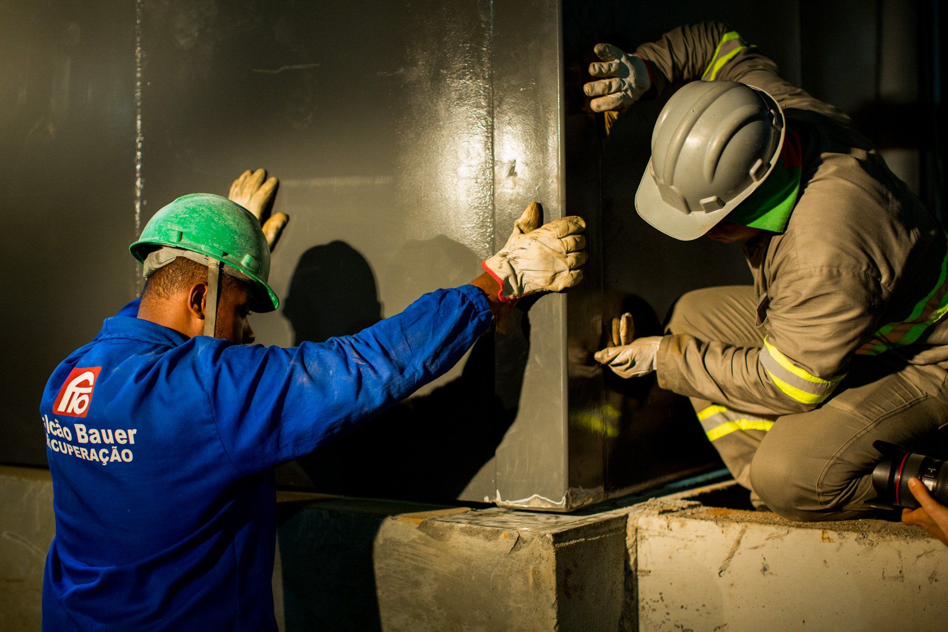 Dois trabalhadores da construção civil usando capacetes estão trabalhando em uma parede.