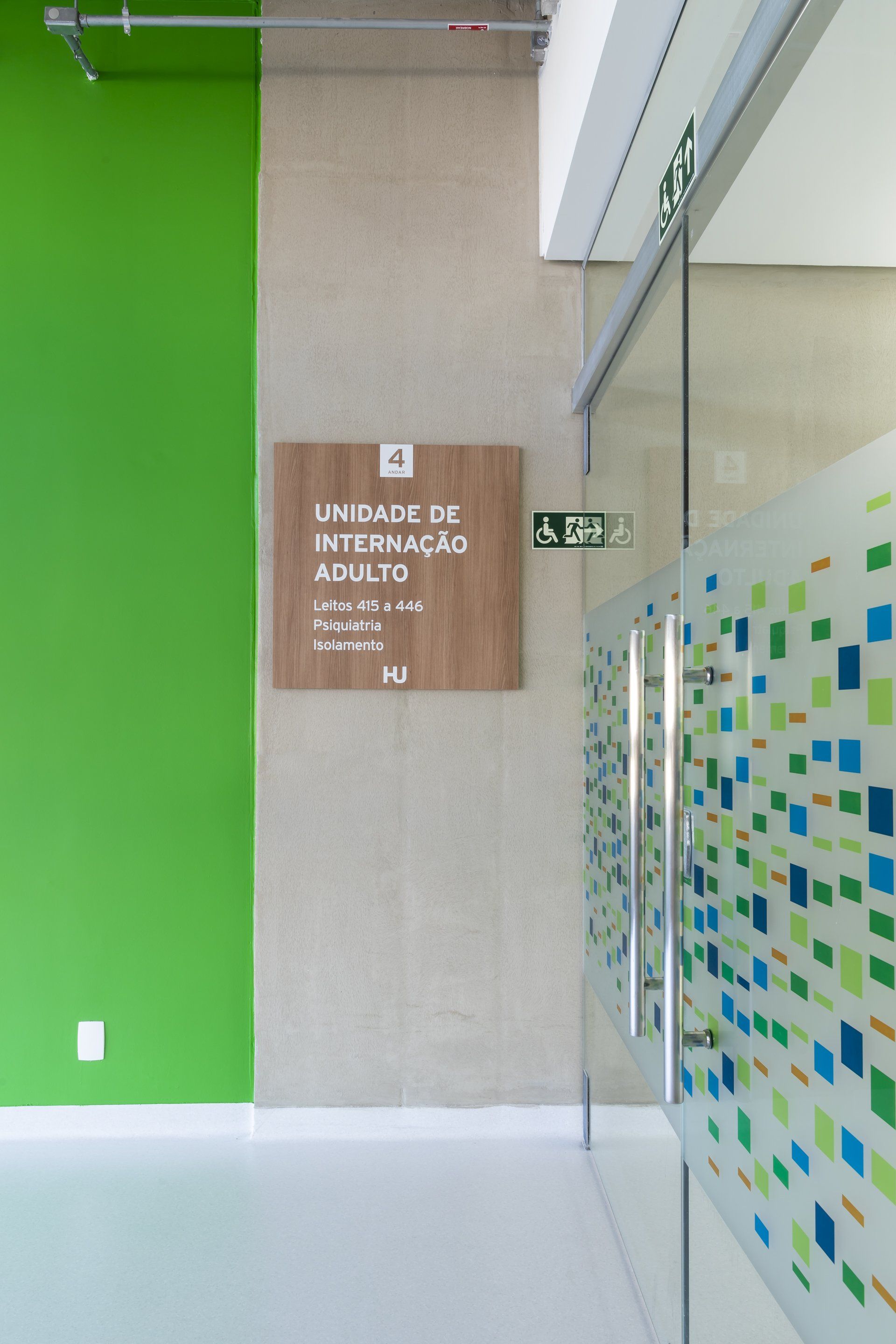 Um corredor com uma parede verde e uma placa na parede.