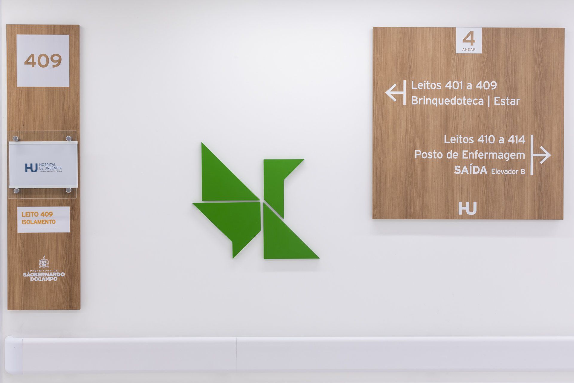 Uma parede branca com uma placa de madeira e um triângulo verde.