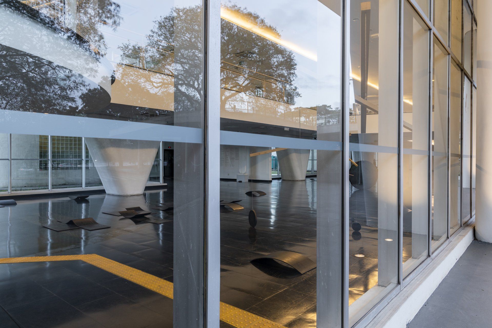 Um prédio com muitas janelas e reflexo de árvores nas janelas.